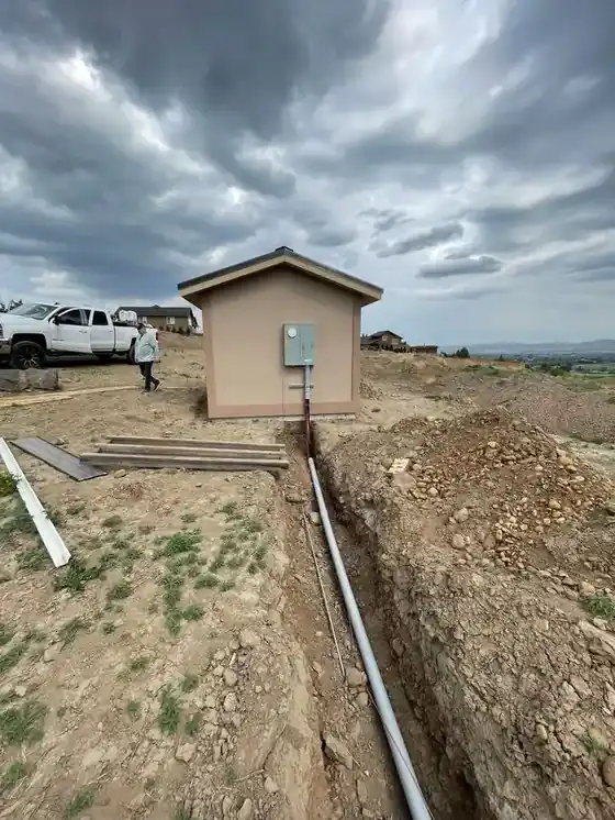 New pump house with a conduit trench running to it under storm clouds