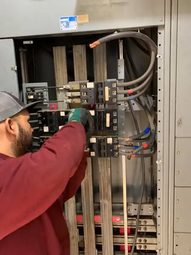 Castle electrician working inside a large commercial breaker panel